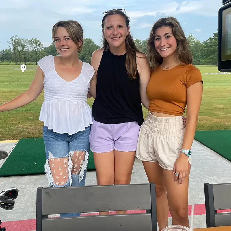 3 young women pose at the driving range - Golfsuites