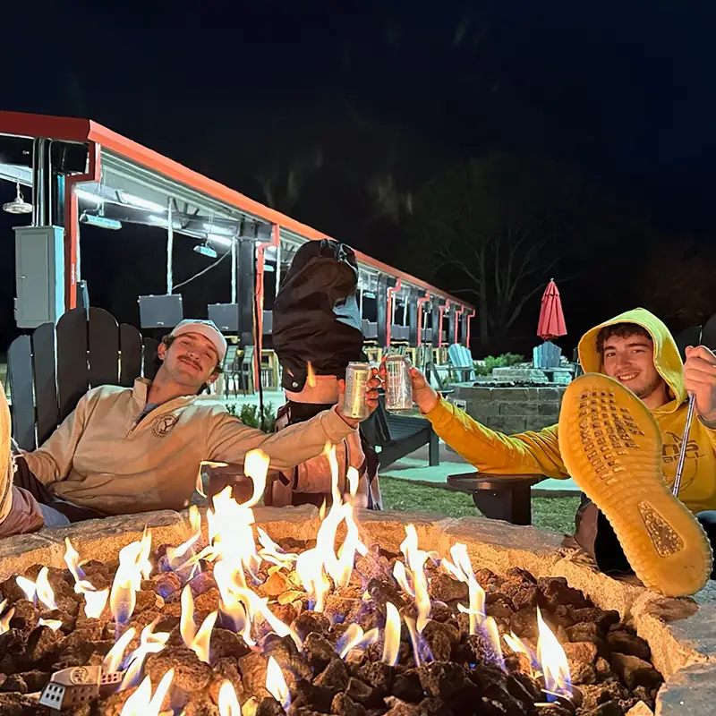 Golfsuites is open late, two men enjoying a drink around a fire pit.