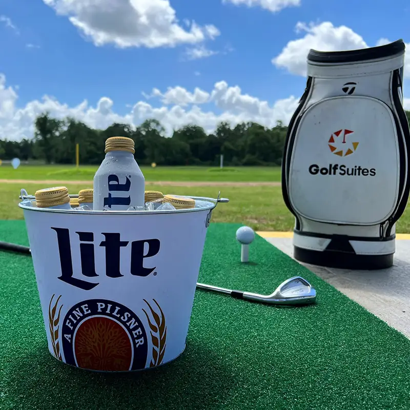 A picture of a driving range up close with a golf bag and drinks