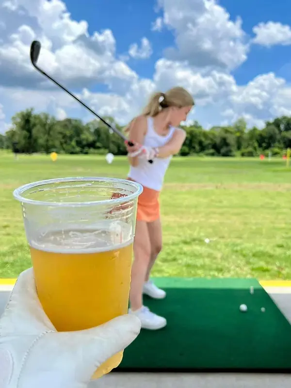 Someone having a drink while waiting their turn at the driving range - golfsuites